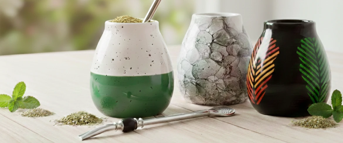 Yerba mate -tarvikkeet: erilaisia yerba mate -kuppeja ja bombilla puupöydällä